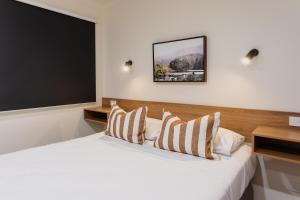 a bedroom with a white bed with a large screen at Coomera Lodge Hotel in Gold Coast
