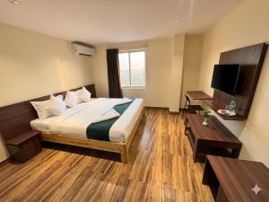 a hotel room with a bed and a television at De Classico Hotel - HBR Layout in Bangalore