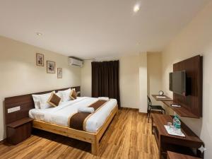 a hotel room with a bed and a desk and a television at De Classico Hotel - HBR Layout in Bangalore +11 photos