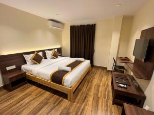 a hotel room with a bed and a flat screen tv at De Classico Hotel - HBR Layout in Bangalore