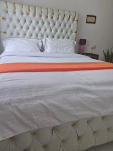 a large white bed with an orange and white blanket at Maroon House in Narok