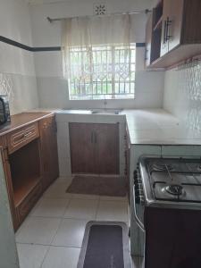 a small kitchen with a stove and a window at Maroon House in Narok
