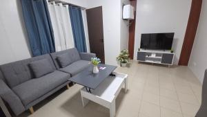 a living room with a couch and a tv at Plumera Mactan Condominium near Airport in Bankal