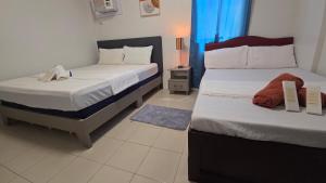a bedroom with two beds and a blue window at Plumera Mactan Condominium near Airport in Bankal +34 photos
