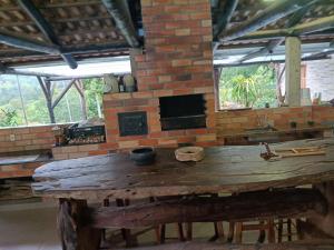 a room with a wooden table and a brick fireplace at Sítio dos Nogueira in Pará de Minas