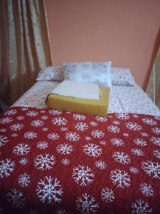 a bed with a red blanket with snowflakes on it at Carol Resident in The Grove