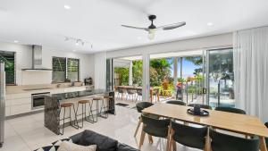 an open kitchen and living room with a table and chairs at Sandveil Absolute Beachfront Access House in Trinity Beach