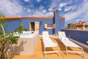 a patio with a hot tub and chairs on a blue building at Spaccavento Boutique Rooms in Chioggia
