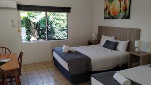 a bedroom with a bed and a table and a window at Tully Motel in Tully