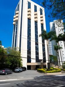 a tall white building with cars parked in a parking lot at Flat Hotel Sena Madureira_Ibirapuera (Apto 708) in São Paulo