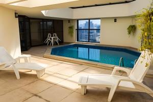 a swimming pool with two chairs and a table at Flat Hotel Sena Madureira_Ibirapuera (Apto 708) in São Paulo