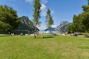 a park with people sitting on the grass near a lake at Traunzeit Apartment in Ebensee