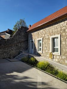 a stone building with a white door and a brick wall at Apartmani PASHA in Nikšić