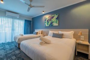 two beds in a hotel room with blue walls at Cairns Southgate Hotel in Cairns