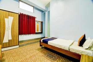 a bedroom with a bed and a red curtain at Hotel O NANDINI in Dibrugarh +27 photos