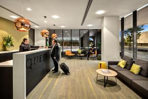 a man and a woman standing at a counter in a lobby at Quest Dandenong Central in Dandenong