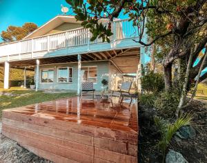 a house with a deck with two chairs on it at Patons Rock Cutie in Rangihaeata