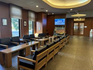 a waiting room with tables and chairs and a screen at Hotel Route-Inn Mooka in Mooka