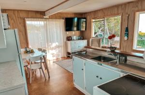 a kitchen with a sink and a table with a dining room at Patons Rock Cutie in Rangihaeata +6 photos