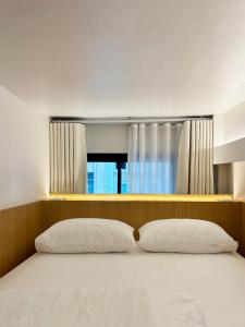 a bed with two pillows in a room with a window at Monomer Hostel Bangkok in Bangkok