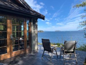 two chairs on a patio with a view of the water at Beach Kayaks Hot Tub Private Cottage in Friday Harbor