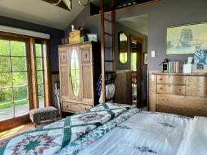 a bedroom with a bed and a dresser and windows at Beach Kayaks Hot Tub Private Cottage in Friday Harbor