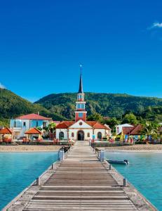 a church on the beach with a dock and water at Bungalow confortable et calme sud de la Martinique in Rivière-Salée