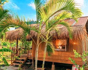 a hut with palm trees in front of it at Family Batcave Homestay in Battambang