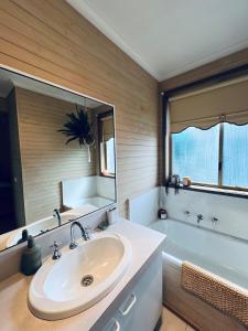 a bathroom with a sink and a tub and a mirror at Hannahs Haven in Traralgon