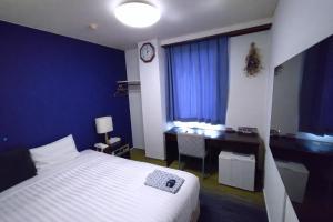 a bedroom with a bed and a desk with a clock at Business Hotel Hayashiso in Miyazaki