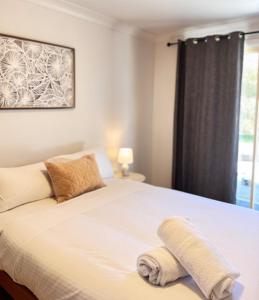 a bedroom with a white bed with a towel on it at Pine Cabin Right A Short Stroll to Zig Zag Railway in Clarence