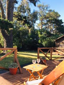 a wooden deck with a table and two wine glasses at Gasty Ranch in Mar del Plata