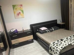 a bedroom with a bed and a dresser and a painting at Apartament Home M in Drobeta-Turnu Severin