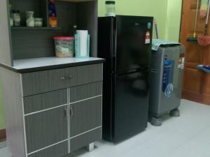 a kitchen with a black refrigerator and a trash can at Homestay Adilah A in Pasir Puteh