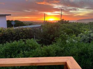a sunset over a field with a wooden bench at Beacon Point House in Port Campbell