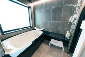 a bathroom with a tub and a chair in it at atsumaro in Minamiboso