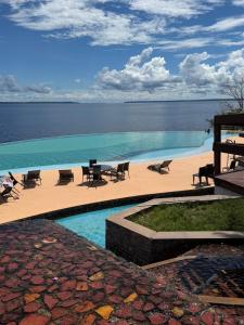 a swimming pool with tables and chairs and the ocean at Tropical Executive Hotel 804 - Propriedade Particular in Manaus