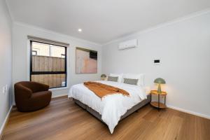 a white bedroom with a bed and a chair at Greenview Place - Officer in Officer