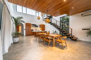 a dining room with a table and chairs and a staircase at Botanique Villa & Studio in Tanah Lot