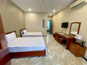 a hotel room with two beds and a television at Nam Phong Hotel & Coffee in Cái Rồng