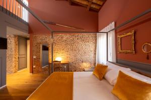 a bedroom with a bed and a brick wall at Spaccavento Boutique Rooms in Chioggia +108 photos