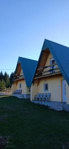a building with a blue roof and some chairs at D&N place - forest house Zabljak in Žabljak