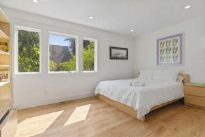 a white bedroom with a bed and two windows at Stunning Views by the Bay 2BR in Brisbane