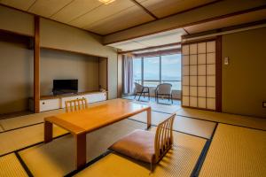 a living room with a table and chairs and a television at 夫婦露天風呂の宿吟松 in Ibusuki