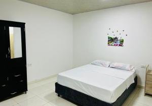 a white bedroom with a bed and a picture on the wall at Hotel Roy in Santa Marta
