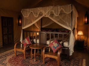 a bedroom with a canopy bed with a table and chairs at Chateau Orientale Resort in Luang Prabang +56 photos