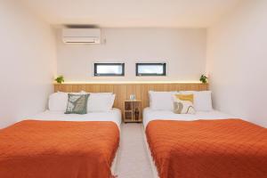 two beds in a room with orange and white at Lucky Today in Osaka