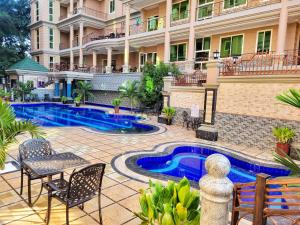 a resort with a pool and chairs and a building at Fountain Palace Hotel & Suites in Kampala