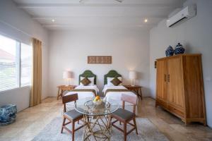 a bedroom with two beds and a glass table at Room & Vespa 4 - Central Seminyak Near Beach in Seminyak