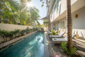 a swimming pool with chaise lounges next to a building at Room & Vespa 4 - Central Seminyak Near Beach in Seminyak